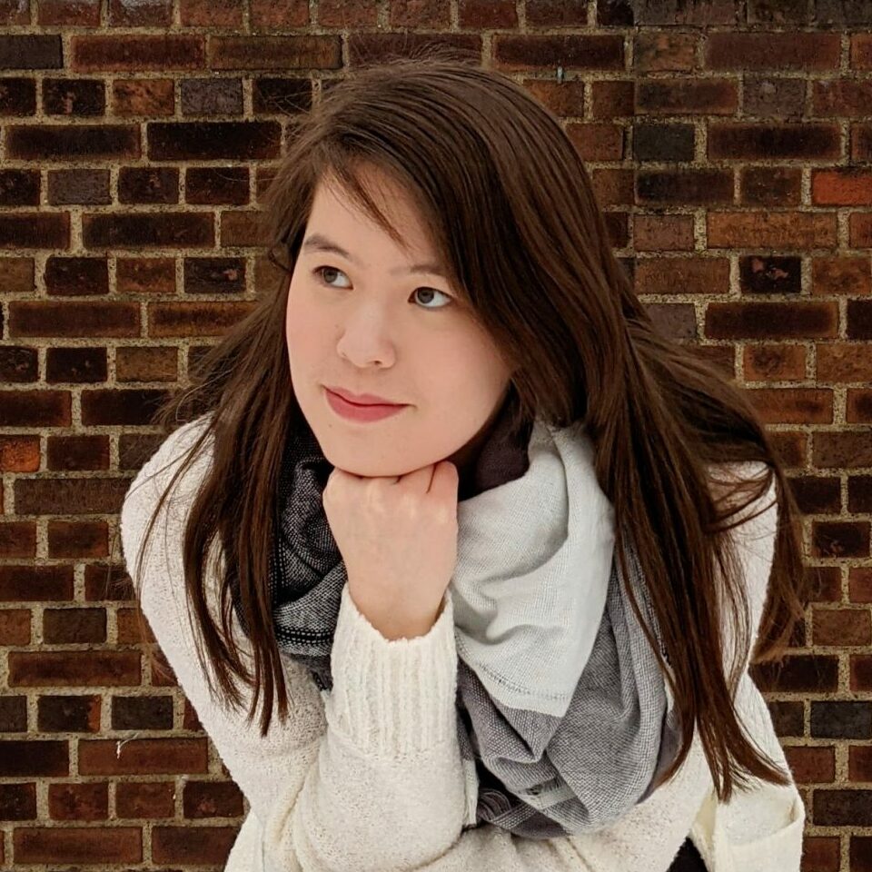 Lori Kipp posing and smiling against a brick wall